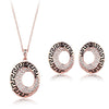 This set features a necklace and earrings with the same pendant/design. It is a long circle in shape, with one small, offset hole through it to the right hand side. Although on the left earring the design is mirrored. Around the outside of the circle is a black line which makes rectangular arches. The inner ring features small crystals for some added shine.
