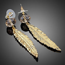  At the base of these earrings are large swarovski crystals which appear amber in colour. In the centre of the crystals are small hoops which the feathers hook through so that they hang down from the crystals.