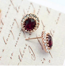  These earrings feature a large ruby, swarovski crystal as the main focus. Surrounding the ruby's are a circle of silver swarovski crystals. The earrings have a rose gold frame and small rose gold prongs which hold the ruby from the sides.
